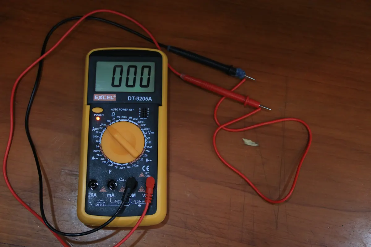A digital multimeter with red and black test leads, the kind of meter used to test motors and capacitors
